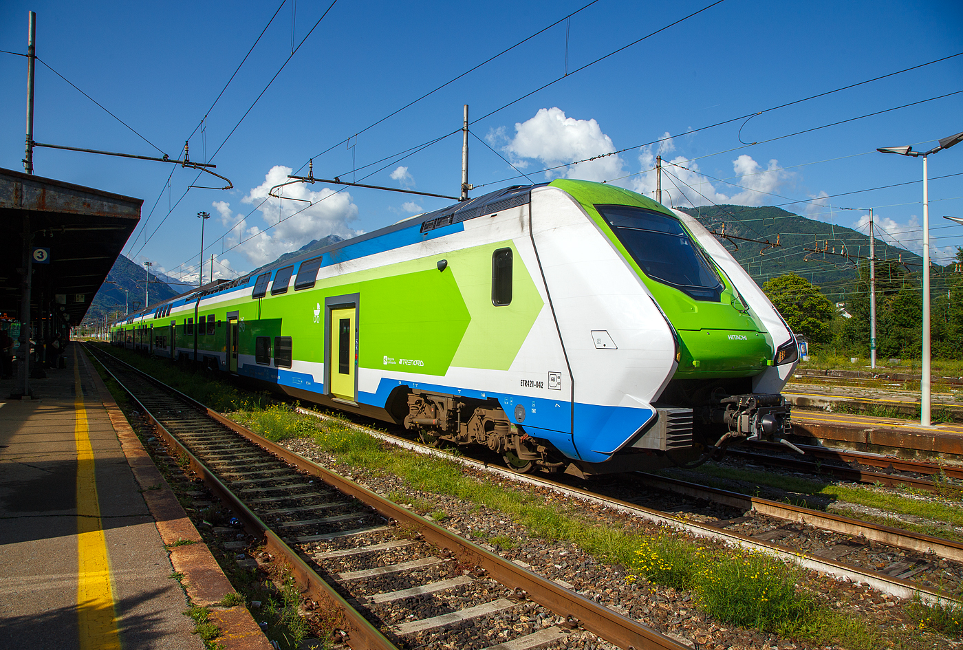 Der Trenord „Caravaggio“ ETR 421-042 (94 83 4441 842-5 I-TN / 94 83 4441 042-0 I-TN) ein vierteilige Hitachi Caravaggio am 25 Mai 2023 im Bahnhof Domodossola. 

Diese Doppelstock-Elektrotriebz�ge vom Typ Hitachi Caravaggio hei�en bekanntlich bei der Trenitalia „Rock“, aber bei der Trenord hei�en sie (wie bei Hitachi) „Caravaggio“. Die Z�ge sind aber sehr �hnlich dem „Rock“ von Trenitalia, der Unterschied liegt wohl in der Innengestaltung. Einige der Z�ge f�r Trenord wurden aber aus der Produktionslinie f�r die Trenitalia entnommen und weisen daher die gleiche Inneneinrichtung auf, w�hrend die �brigen das Trenord-Interieur erhalten haben.

Die Trenord hat z.Z. 105 dieser Doppelstock-Elektroz�ge vom Typ Hitachi „Caravaggio“, als Baureihe ETR 421, ETR 521 oder ETR 521 S1 (ETR steht f�r italienisch Elettro Treno Rapido). Der Unterschied zwischen den beiden f�nfteiligen ETR 521 und ETR 521 S1 (urspr�nglich als ETR 522 vorgesehen) ist mir noch unbekannt.

Caravaggio f�r die FNM
Die Ferrovie Nord Milano unterzeichnete im September 2018 einen Rahmenvertrag �ber maximal 120 Z�ge mit vier oder f�nf Wagen. Ein erster Abruf von 2018 umfasst 30 Vierteiler. Diese Fahrzeuge sind bei der Trenord f�r den Einsatz auf der S-Bahn Mailand vorgesehen. Weitere 10 F�nfteiler wurden f�r den Malpensa Express zum Mail�nder Flughafen und 16 Vierteiler f�r eine Flughafenverbindung in Bergamo bestellt. Ein dritter Auftrag beinhaltet zus�tzliche 10 Vierteiler und 40 F�nfteiler, die ab 2022 ausgeliefert wurden. Insgesamt werden folglich 56 Vierteiler und 50 F�nfteiler ausgeliefert. 

Der Hitachi Caravaggio ist ein elektrischer Doppelstock-Triebzug, der von Hitachi Rail Italia in Reggio di Calabria und Neapel gefertigt wird. Die italienische Trenitalia setzt diesen Typ unter dem Namen „Rock“ im Regionalzugverkehr ein. Ein Folgeauftrag, vier- und f�nfteiligen Z�gen, wurde von den Ferrovie Nord Milano (Trenord) f�r den Nahverkehr rund um Mailand bestellt, hier haben sie den Namen „Caravaggio“

Die Z�ge sind als ETR.421, ETR.521 und ETR.621 im italienischen Baureihenverzeichnis eingereiht, wobei die erste Ziffer die Anzahl der Wagen kennzeichnet. Hitachi nennt die Grundkonstruktion Masaccio. Auf der gleichen Plattform bauen die Blues-Dieseltriebz�ge der Trenitalia auf. Diese sind einst�ckig und mit Akkus ausr�stbar. Namensgeber f�r die Zugtypen sind die italienischen K�nstler Masaccio und Caravaggio, die im 15. und 16. Jahrhundert herausragende Gem�lde schufen.

Der Hersteller Hitachi Rail Italy S.p.A. ist kein unbekannter auf Italiens Schienen, denn Hitachi war bis 2015 noch AnsaldoBreda und war auch an der Entwicklung und Bau der Hochgeschwindigkeitsz�gen ETR 400 (Frecciarossa 1000) beteiligt. Im Jahr 2015 �bernahm der japanische Konzern Hitachi die AnsaldoBreda. Hitachi Rail Italien baut im Werk Pistoia (n�rdlich von Florenz) die doppelst�ckigen Elektrotriebz�ge (EMU) vom Typ „Caravaggio“. In Neapel werden die Drehgestelle und Komponenten gebaut.

Bauart / Aufbau
Die Z�ge bestehen aus vier bis sechs Doppelstockwagen. Jeder Wagen besitzt zwei einfl�gelige T�ren im Unterstock pro Wagenseite. Ein Wagenteil ruht jeweils auf 2 luftgefederten Drehgestellen, die Frontwagen besitzen jeweils 2 Triebdrehgestelle mit je zwei TSA-Gleichstrommotoren, so ergibt sich ein Gesamt-Stundenleistung von 3.400 kW. Die sechsteiligen EMU haben zudem in der Mitte noch ein weiteres Wagenteil mit 2 Triebdrehgestellen, so haben die ETR 621 die Achsfolge Bo′Bo′+2′2′+2′2′+Bo′Bo′+2′2′+Bo′Bo′ und eine Gesamt-Stundenleistung von 4.200 kW (vermutlich gedrosselte Leistung). Die Z�ge sollen 30 % weniger Energie pro Passagierkilometer verbrauchen und mehr Passagiere pro Wagenl�nge bef�rdern k�nnen als fr�here Modelle.

Jeder Zug wird von einem 3-kV-Gleichstromsystem angetrieben, dass 3.400 kW (4.600 PS) erzeugt und eine H�chstgeschwindigkeit von 160 km/h (99 mph) erreicht. Die Antriebsausr�stung ist gr��tenteils auf dem Dach montiert, wodurch der Innenraum optimal f�r die Unterbringung der Passagiere genutzt werden kann. Die Beschleunigung des Zuges betr�gt 1,1 m/s�, was zu einer verbesserten P�nktlichkeit beitr�gt. Der Zug ist mit seitlichen und nach vorne gerichteten Kameras mit Anomalie-Erkennung ausgestattet. Der Wagenkasten besteht haupts�chlich aus Leichtmetalllegierungen, was ein geringes Gewicht pro Passagier und eine hohe Passagierkapazit�t pro L�ngeneinheit erm�glicht. Die Passagierkapazit�t variiert je nach Betreiber.

Ein Zug ist zu einem einzigen durchg�ngigen barrierefreien Raum, ohne T�ren oder Trennw�nde, angeordnet. Der neue Zug besitzt sehr gro�e Fenster. Die Z�ge verf�gen �ber Klimaanlagen, die sich an die Anzahl der Fahrg�ste an Bord anpasst, um den Energieverbrauch zu senken. Jeder f�nfteilige hat zehn T�ren/Seite (vierteilige 8) und zwei Toiletten (eine Standardtoilette und eine f�r Personen mit eingeschr�nkter Mobilit�t). Zwei Bereiche in der N�he der barrierefreien Toiletten sind f�r Rollst�hle reserviert und verf�gen �ber Andockm�glichkeiten und Serviceruftasten. Der Caravaggio verf�gt �ber Gep�ckablagebereiche und spezielle Stellpl�tze f�r Fahrr�der und Kinderwaagen, sowie Steckdosen zum Aufladen von Elektrofahrr�dern. Die Z�ge sind mit LED-Beleuchtung, WLAN, USB-Anschl�ssen, einem Fahrgastinformationssystem, Energiez�hlern und einem Fahrgastz�hler ausgestattet. Treppen �ber den Drehgestellen erm�glichen den Zugang zum Oberdeck. Die T�ren sind mit Schiebetritten ausgestattet, um den Spalt zwischen Bahnsteig und Fahrzeug zu �berbr�cken, wenn der Zug steht. F�r Fahrg�ste mit eingeschr�nkter Mobilit�t steht zudem eine manuell bedienbare Rampe zur Verf�gung.

TECHNISCHE DATEN der ETR 421 (4-Teiler):
Typ: Hitachi Caravaggio
BR / Bezeichnungen: ETR 421, bei TN „Caravaggio“ und bei Trenitalia „Rock“
Baujahre: ab 2017
Spurweite: 	1.435 mm (Normalspur)
Fahrzeugbegrenzungslinie: GB
Achsfolge: Bo'Bo '+ 2'2' + 2'2 '+ Bo'Bo' 
L�nge �ber Puffer: 109.600 mm 
Breite: 2.800 mm
H�he �ber SO (ohne Stromabnehmer): 4.300 mm
Drehzapfenabst�nde (je Wagen): 19.100 mm
Achsabstand im Drehgestell: 2.650 mm
Treib- und Laufraddurchmesser: 920 mm (neu)
H�chstgeschwindigkeit: 160 km/h
Eigengewicht: ca. 204,0 t
Max. Achslast: 18,5 t
Beschleunigung:  1,10 m/s�
Anzahl der Motoren: 8 luftgek�hlte TSA-Gleichstrommotore
Traktionsmotoren: Typ TME 59A-22-4 von TSA - Traktionssysteme Austria GmbH (Wiener Neudorf)
Stundenleistung: 3.400 kW (4.622 PS)
Stromsystem: 3.000 V DC (=)
Sitzpl�tze: ca. 479 
Toiletten: 2 geschlossenes System, davon 1 Rollstuhlgerecht
T�ren je L�ngsseite: 8
Kupplung: Scharfenbergkupplung (SCHAKU) Typ 10
Bremse: KB R-E-A (D)

Abweichende TECHNISCHE DATEN der ETR 521 (5-Teiler):
BR / Bezeichnungen: ETR 521, bei TN „Caravaggio“ und bei Trenitalia „Rock“
Achsfolge: Bo'Bo '+ 2'2' + 2'2 '+ 2'2 '+ Bo'Bo' 
L�nge �ber Puffer: 136.800 mm
Sitzpl�tze: ca. 600
T�ren je L�ngsseite: 10

Abweichende TECHNISCHE DATEN der ETR 621 (6-Teiler):
BR / Bezeichnungen: ETR 621, bei Trenitalia „Rock“
Achsfolge: Bo'Bo '+ 2'2' + 2'2 '+ Bo'Bo' + 2'2 '+ Bo'Bo' 
L�nge �ber Puffer: 163.400 mm
Anzahl der Motoren: 12 luftgek�hlte TSA-Gleichstrommotore
Stundenleistung: 4.200 kW (5.710 PS), gedrosselt
Sitzpl�tze: ca. 720
T�ren je L�ngsseite: 12

Quellen: Trenord, Trenitalia, Hitachi, TSA, Anschriften an den ETR, Wikipedia (D und I) 
Stand: September 2025