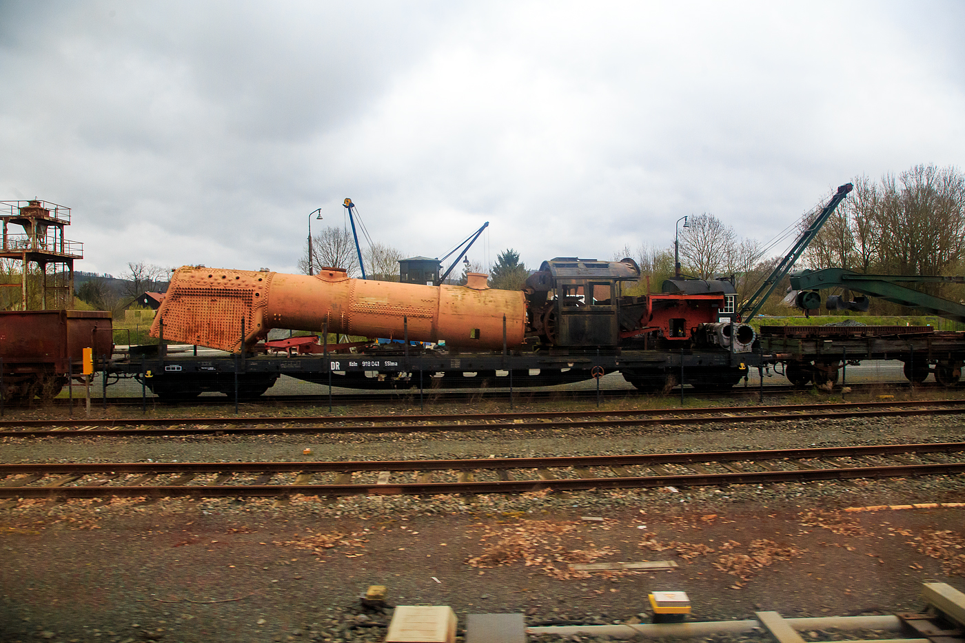 Der vierachsige Drehgestell-Schienenwagen (Drehgestell-Flachwagen) DR Köln 918 041 SSlma (DB SSlma 44), beladen mit Kessel und Teilen einer Dampflok, am 17 April 2023 im DDM - Deutsches Dampflokomotiv-Museum in Neuenmarkt (aufgenommen aus einem Zug heraus).

Mit dem Aufkommen der Schweißtechnik und der Aufrüstung des Deutschen Reiches entstand Bedarf an einem neuen vierachsigen Schienenwagen. 1934 lieferte SEAG (Siegener Eisenbahn Bedarf AG in Dreis-Tiefenbach) die ersten beiden Versuchswagen. Sie bestanden aus St 52 und hatten jeweils ein abnehmbares Bremserhaus aus Holz oder Stahl. Die weiteren Lieferungen bis 1939 bestanden ebenfalls aus St 52, hatten drei Querträger und sieben Rungenpaare. Das Bremserhaus war abnehmbar. Ab 1941 baute man eine veränderte Variante. Diese bestand jetzt aus dem schwächeren St 37, was dazu führte, dass man einen vierten Querträger vorsehen musste. Seitlich gab es jetzt nun acht Rungenpaare (wie bei diesem). Für Fahrzeugtransporte hatte der Bremserstand nur noch ein umlegbares Bühnengeländer. Neben den Lieferungen an die DR erhielt auch die Wehrmacht diese Wagen und setzte sie für militärische Zwecke, u.a. in den Zügen der mobilen V2-Rampen, ein. Insgesamt wurden bis Kriegsende ca. 3.500 Wagen gebaut. Nach 1945 waren die geschweißten Schienenwagen über halb Europa verteilt. Die DB hatte nach Kriegsende ca. 1.400 Wagen im Bestand, die DR schätzungsweise 500. Bei beiden Bahnverwaltungen wurden die Wagen lange eingesetzt und schieden erst in den 1980er-Jahren aus. Noch 1979 hatte die DB über 1.000 der als R 672 bezeichneten Wagen im Einsatz. 
