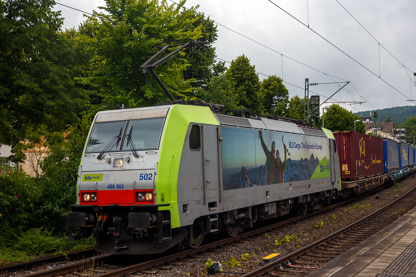 Die BLS Cargo 502, Re 486 502-8/E 486 502 SF  The Alpinists in Europa  (91 85 4486 502-8CH-BLSC) fährt am 07 Juli 2025 mit einem HUPAC KLV-Zug durch Kirchen (Sieg) in Richtung Köln.

Nochmals einen lieben Gruß an den netten Lokführer zurück.

Die TRAXX F140 MS wurde 2008 von Bombardier in Kassel unter der Fabriknummer 34401 gebaut und an die BLS Cargo AG (Bern) geliefert. Die Loks sind nur für die Schweiz, Deutschland, Österreich und Italien zugelassen.

Der Erfolg im Güterverkehr veranlasste die BLS zehn weitere TRAXX zu bestellen im Gegensatz zur ersten Serie TRAXX F140 AC1 mit der Bezeichnung Re 485 001 bis 485 020, die nur unter Wechselstrom fahren können, können die TRAXX F140 MS Re 486 501 bis 486 510 auch unter 3.000 Volt Gleichstrom eingesetzt werden. Bombardier hatte seit der ersten Lieferung Verbesserungen vorgenommen. Dabei wurde der Lokomotivkasten optimiert und die Traktionsausrüstung mit moderneren Komponenten versehen. Eine Nachbeschaffung wäre noch möglich gewesen, hätte aber dazu geführt, dass die Lokomotiven nicht auf dem neuesten Stand waren und nicht unter der Gleichstromfahrleitung eingesetzt werden konnten. Die eingebauten Zugbeeinflussungssysteme erlauben den Einsatz in Deutschland, Österreich, der Schweiz und Italien (DACHI). Anfänglich waren die Lokomotiven in der Schweiz nur für den Einsatz auf Strecken mit konventioneller Zugbeinflussung und nicht auf ETCS Level 2 Strecken zugelassen. Die Re 486 können unter sich und mit den Re 485 und Lokomotiven der Baureihe 185/186 in Vielfachsteuerung eingesetzt werden. Mittlerweile nach Umbauten durch die BLS, können die Loks nun auch mit Re 465, sowie mit Siemens Vectron der BR 193 bzw. Re 475 in Mehrfachtraktion gefahren werden.

TECHNISCHE DATEN:
Spurweite: 1.435 mm (Normalspur)
Achsformel: Bo’Bo’
Länge über Puffer: 18.900 mm
Höhe: 4.385 mm
Breite: 2.978 mm
Drehzapfenabstand: 10.400 mm
Achsabstand im Drehgestell: 2.600 mm
Dienstmasse: 85 t
Höchstgeschwindigkeit:  140 km/h
Dauerleistung: 5.600 kW
Dauerzugkraft: 300 kN
Treibraddurchmesser: 1.250 mm
Stromsysteme: 15 kV 16,7 Hz, 25 kV 50 Hz Wechselstrom sowie 3 kV und 1,5 kV Gleichstrom
Antrieb: Tatzlager