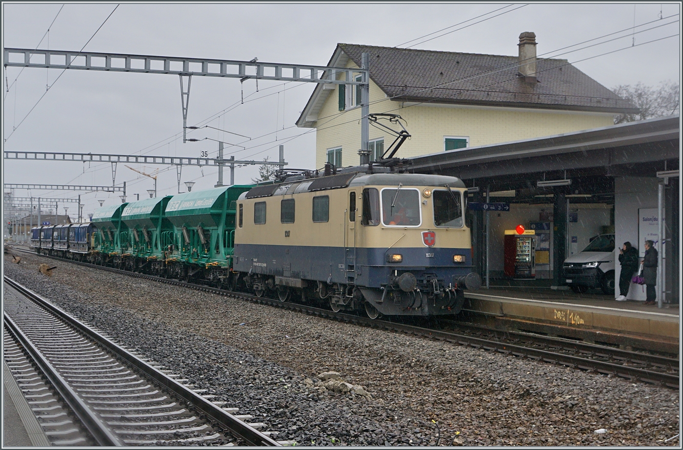 Die IRSI Re 4/4 II 11387 (Re 421 387-2) hat mit ihrem Kieszug das Kieswerk verlassen und ist nun auf Gleis 1 in Gland für die Rückfahrt nach Morges bereit. 

22. Feb. 2024
