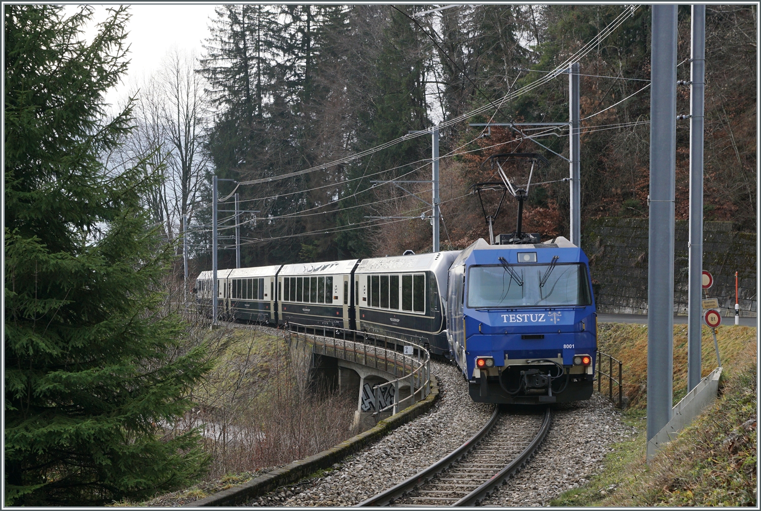 Die MOB Ge 4/4 8001 ist als Schublok mit dem GoldenPass Express 4065 von Interlaken nach Montreux unterwegs. Die Ge 4/4 8001 hat den Zug in Zweisimmen übernommen und rollt nun kurz nach der 93 Meter langen Pont Gardiol, welche den Bois des Chenaux überbrückt, ihrem Ziel Montreux entgegen.

4. Januar 2023 