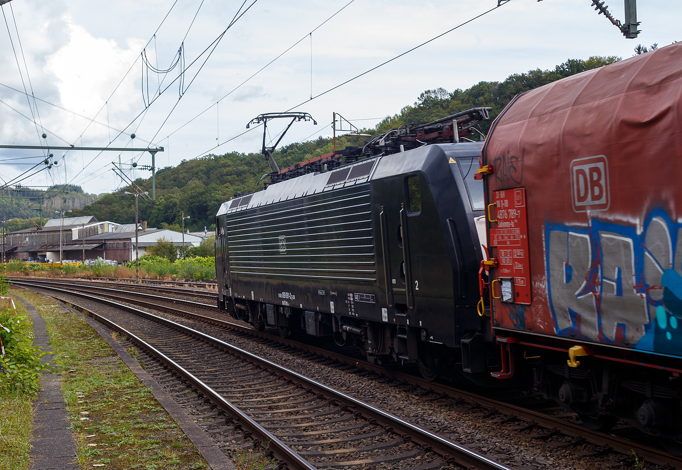 Die schwarze 189 091-2 (91 80 6189 091-2 D-DB, Class 189- VJ) der DB Cargo AG, MRCE Dispolok ES 64 F4-991, fährt am 11 September 2024, mit einem Coilzug (sechsachsigen Drehgestellflachwagen mit verschiebbarem Planenverdeck und Lademulden für Coils, der Gattung Sahimms-tu 900.2), durch den Bahnhof Scheuerfeld (Sieg) in Richtung Betzdorf bzw. Siegen.

Die SIEMENS EuroSprinter ES 64 F4 wurde 2005 von Siemens in München-Allach unter der Fabriknummer 21077 gebaut und in der Variante B, an die damalige Railion Deutschland AG ausgeliefert und war nur für Deutschland zugelassen. Im Jahr 2006 wurde sie an die MRCE Dispolok verkauft, wo sie die Bezeichnung ES 64 F4-991 (91 80 6189 091-2 D-DISPO) trug. 2008 wurde sie dann in die Variante J umgebaut und hat so nun die Zulassungen für Deutschland und die Niederlande. Unteranderem war sie an die ERSR, LTE, RRF und die SBB Cargo International AG vermietet. Im November  2021 wurde sie dann an die DB Cargo AG verkauft.

Die BR 189 (Siemens ES64F4) hat eine Vier-Stromsystem-Ausstattung, diese hier hat die Variante J (Class 189-VJ) und besitzt so die Zugbeeinflussungssysteme LZB/PZB, ETCS und ATB für den Einsatz in Deutschland und den Niederlanden.
Die Stromabnehmerbestückung ist folgende:
Pos. 1: D, NL (AC)
Pos. 2: NL (DC)
Pos. 3: NL (DC)
Pos. 4: D, NL (AC)