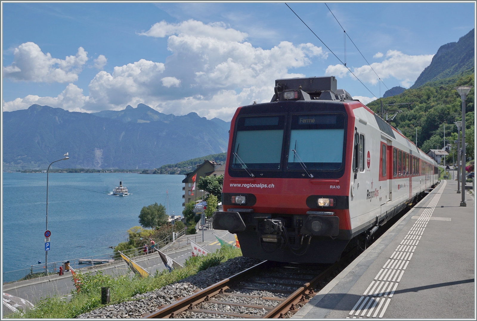 Ein RegionAlpes Regionalzug ist in St-Gingolph am Ziel seiner langen Fahrt von Brig angekommen. Im Hintergrund auf dem Genfersee ist ein Raddampfer zu erkennen, welcher die  Tour du Haut Lac  fährt (Vevey- Villeneuve - Bouvertet - St-Gingolph - Vevey).

30. Juli 2022 