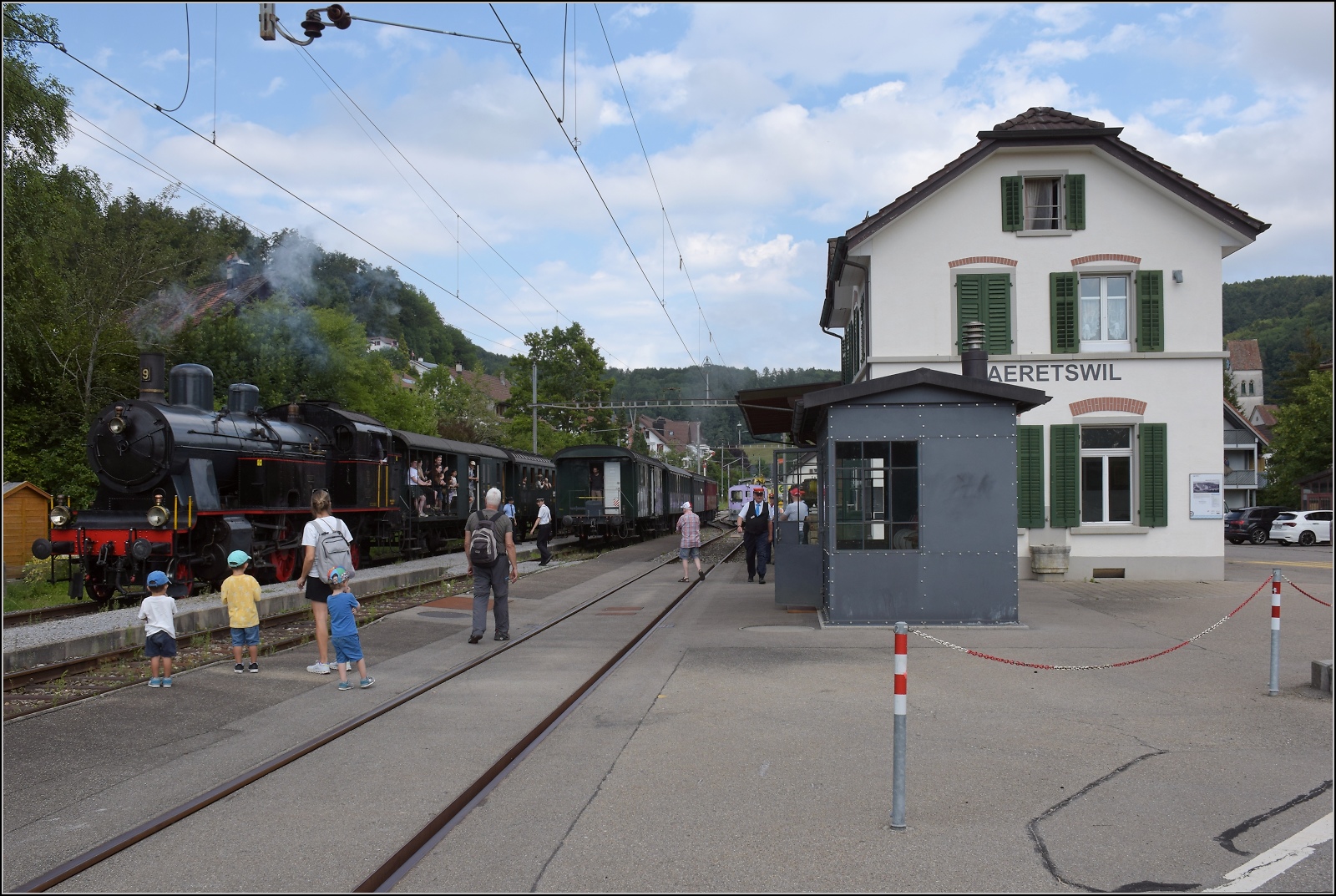Fahrtag im Z�rcher Oberland. 

Eb 3/5 der BT, heute durch den DLC betreut, im Bahnhof B�retswil. Man beachte die allseitige Begeisterung und das vorbildlich restaurierte Stellwerk. Juli 2023.