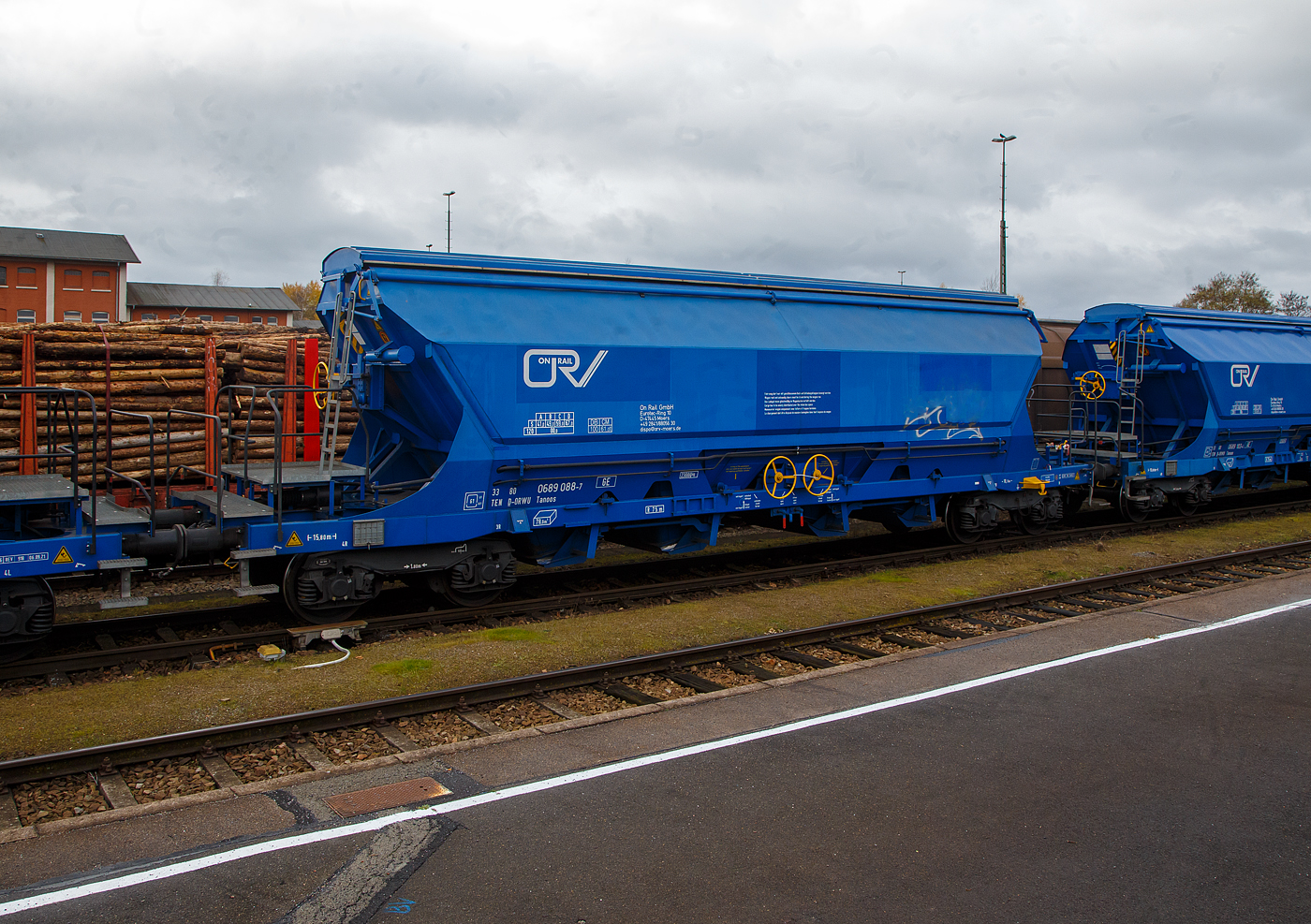 Gedeckter vierachsiger Drehgestell-78m³-Schüttgutwagen mit Schwenkdach und schlagartiger mittigen Schwerkraftentladung (Mittenselbstentladewagen) 33 80 0689 088-7 D-ORWU, der Gattung Tanoos, der Waggonvermietungsfirma On Rail GmbH (Mettman), abgestellt am 24.11.2022 im Bahnhof Schwandorf.

Der Wagen ist für den Transport von nässeempfindlichen Schüttgütern insbesonders korrosiv wirkenden, wie Kali sowie andere Düngemittel und Salze in granulierter Form, geeignet. Aus diesem Grund sind besonders gefährdete Bauteile und Berührungsstellen aus korrosionsfestem Stahl gefertigt. Der Wagenkasten besteht aus einem trichterförmigen Behälter, ist durchgängig und nur zwischen den Auslauföffnungen unterteilt. Die Entladung erfolgt über pyramidenförmige Auslauftrichter, die vier mittig angeordneten Entladeschieber werden paarweise über je ein Handrad betätigt. Alle Ecken und Aussteifungen sind durch Ausrundungen so gestaltet, dass sich nahezu keine Ladegutreste festsetzen können. Schräggestellte Behälterwände haben eine Neigung von 55° bzw. 60° zur Horizontalen. Der Wagenkasten ist so gestaltet, dass er von außen maschinell gereinigt werden kann. Die zweischalige Konzeption des manuell bedienbaren Dachs ist mit einer Kippeinrichtung versehen, die eine optimale Innenreinigung ermöglicht.

TECHNISCHE DATEN:
Hersteller: ELH Waggonbau Niesky GmbH
Spurweite: 1.435 mm
Länge über Puffer : 15.800 mm
Drehzapfenabstand: 10.760 mm
Achsabstand im Drehgestell: 1.800 mm
Laufraddurchmesser: 920 mm (neu)
Eigengewicht: 23.000 kg
Höchstgeschwindigkeit:  100  km/h (beladen) / 120 km/h (leer)
Maximales Ladegewicht: 67,0 t (Streckenklasse D oder höher)
Nat. max. Ladegewicht auch: 61, 0 t (DB Streckenklasse CM - 21 t Radsatzlast)
Kleinster bef. Gleisbogenradius: 75 m
Rauminhalt: 78 m³
Bremse: KE-GP-A (K)
Bremssohle: S517 / C 810
Intern. Verwendungsfähigkeit: TEN-GE

Die Bedeutung der Gattungs- und Kennbuchstaben (hier Tanoos):
T - Wagen mit öffnungsfähigem Dach 
a - mit vier Radsätzen
n - mit vier Radsätzen höchste Lastgrenze über 60 t
oo - mit Schwerkraftentladung, schlagartig, mittig, tiefliegend
s - Höchstgeschwindigkeit 100 km/h (beladen)