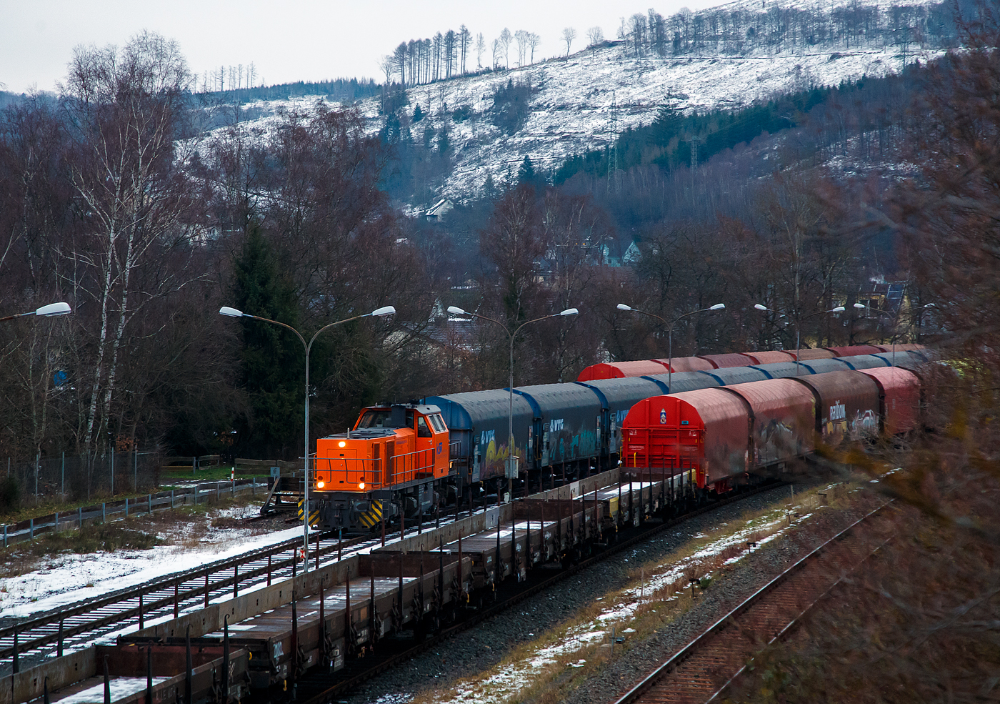 Güterverkehr gibt es noch in Herdorf....
Die KSW 44 (92 80 1271 004-4 D-KSW) eine MaK G 1000 BB der KSW (Kreisbahn Siegen-Wittgenstein), eine MaK G 1000 BB, steht am späten Nachmittag des 24.01.2023 mit einem Coilzug auf dem KSW Rangierbahnhof Herdorf (Freien Grunder Eisenbahn KSW NE447 / DB-Nr. 9275).

Normalerweise läuft der Güterverkehr auf dem Streckenanschnitt Herdorf – Betzdorf, aber der ist bis min. Ende April gesperrt, so muss die KSW den Umweg über Haiger fahren. Aber es ist nicht nur der Umweg, für den Güterverkehr ist noch die Streckenklasse sehr entscheidend und die beträgt bei dem Streckenanschnitt Herdorf – Haiger nur CE (anstatt D4 zwischen Betzdorf und Herdorf). Bei CE beträgt die Radsatzlast max. 20 t bei D4 aber 22,5 t. Dadurch kann ein Coil weniger geladen werden, da man nicht gerademal Coils vierteln kann, ergibt sich daraus ein bis zu 35% geringeres Ladegewicht und ein Mehraufwendung von Waggons.
