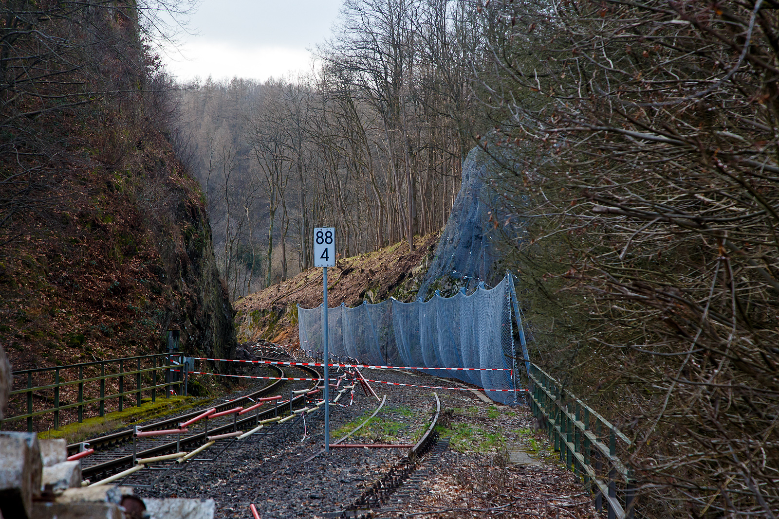 HLB Zug am 23.12.2022 auf der Hellertalbahn entgleist und die Strecke bleibt weiter, vermutlich bis Juni 2023 lange gesperrt...
Die Strecke der Hellertalbahn (KBS 462), vom Hp Königsstollen in Richtung Betzdorf gesehen am 04.02.2023. Hier sieht man Tatsache das rechts vom Gleis bereits umfangreiche Hangsicherungsmaßnahmen stattgefunden haben. Leider gab es am 23.12.2022 einen Erdrutsch (bei km 88,4) auf der linken Seite und ein Triebwagen entgleiste. Verletzt wurde zum Glück niemand.

Derzeit muss man von einer Sperrung der Hellertalbahn bis zum Juni ausgehen. Ja, die Sicherheit geht vor!!! Aber ist wirklich keine kurzfristige Maßnahme möglich. 

Neben der Sperrung der Bahn, gibt es in Herdorf wegen Straßenbauarbeiten schon genug Probleme mit dem Umleitungsverkehr auf den Straßen. Hinzu kommt ab Anfang April ein weiteres Problem in der Verbindung zwischen Betzdorf und Herdorf, denn dann wird der vom Landesbetrieb Mobilität beauftragte Abriss und Neubau der Hellerbrücke in Herdorf beginnen. Die L284 soll dafür bis August gesperrt bleiben und in den ersten sechs Wochen auch die wichtige Umleitungsverbindung über die L285 nach Daaden. 