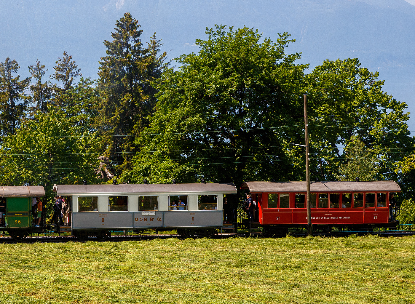 Im Zugverband am 27 Mai 2023 eines BC Zuges bei Chaulin, links der vierachsige zweite Klasse Personenwagen mit zwei Plattformen MOB ex B⁴ 61 und rechts am Zugschluss der zweiachsige  zweite Klasse (Nichtraucher) / dritte Klasse (Raucher) Großraum-Plattformwagen ex CEV BC² 21, beide der Museumsbahn Blonay-Chamby.