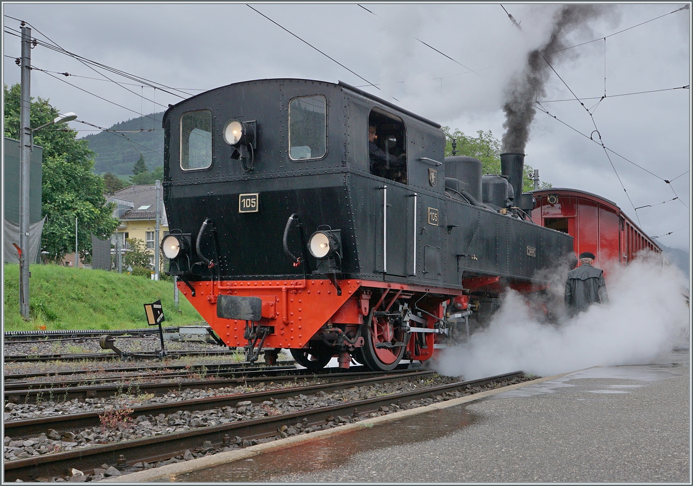Kräftig dampfend verlässt die abgekuppelte SEG G 2x 2/2 105 der Blonay Chamby Bahn in Blonay ihren Zug, um ihn zu umfahren.
Gerade  schlechtes Wetter  bietet oft ganz besondere Motive, so dass sich eine Museumsbahnbesuch auch bei Regen lohnt. 

22. Juni 2024