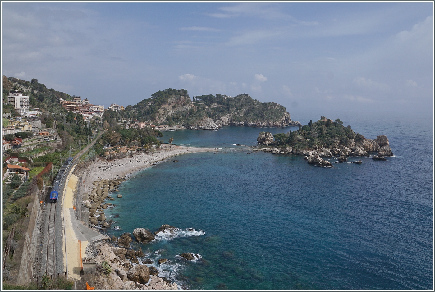 Kurz nach dem Bahnhof von Taormina gleitet der Blick in Richtung Messina zur  Isolla Bella  und einem aus Messina herannahenden FS Trenitalia HTR 412  Blues. Ebenfalls unübersehbar, die wiederhergestellte Infrastruktur der Trasse nach dem schweren Wintersturm vom Januar 2026. 

8. März 2026