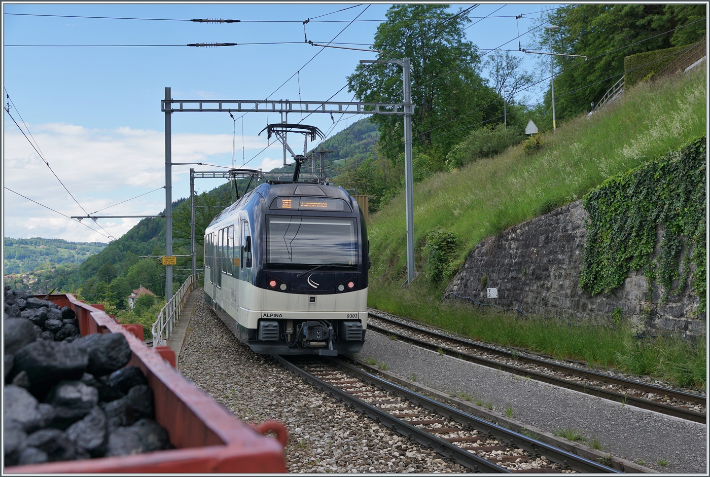 Mit dem MOB ABe 4/4 9303  Alpina  am Schluss des Zuges verlässt ein Regionalzug Montreux -Zweisimmen den Bahnhof von Chamby. Der mit Kohlen beladen Wagen links auf dem Foto wurde absichtlich mit ins Bild genommen, er zeigt den Bezug von Chamby zur Blonay-Chamby Bahn (für welche die Kohle ja auch bestimmt ist). 

19. Mai 2024
