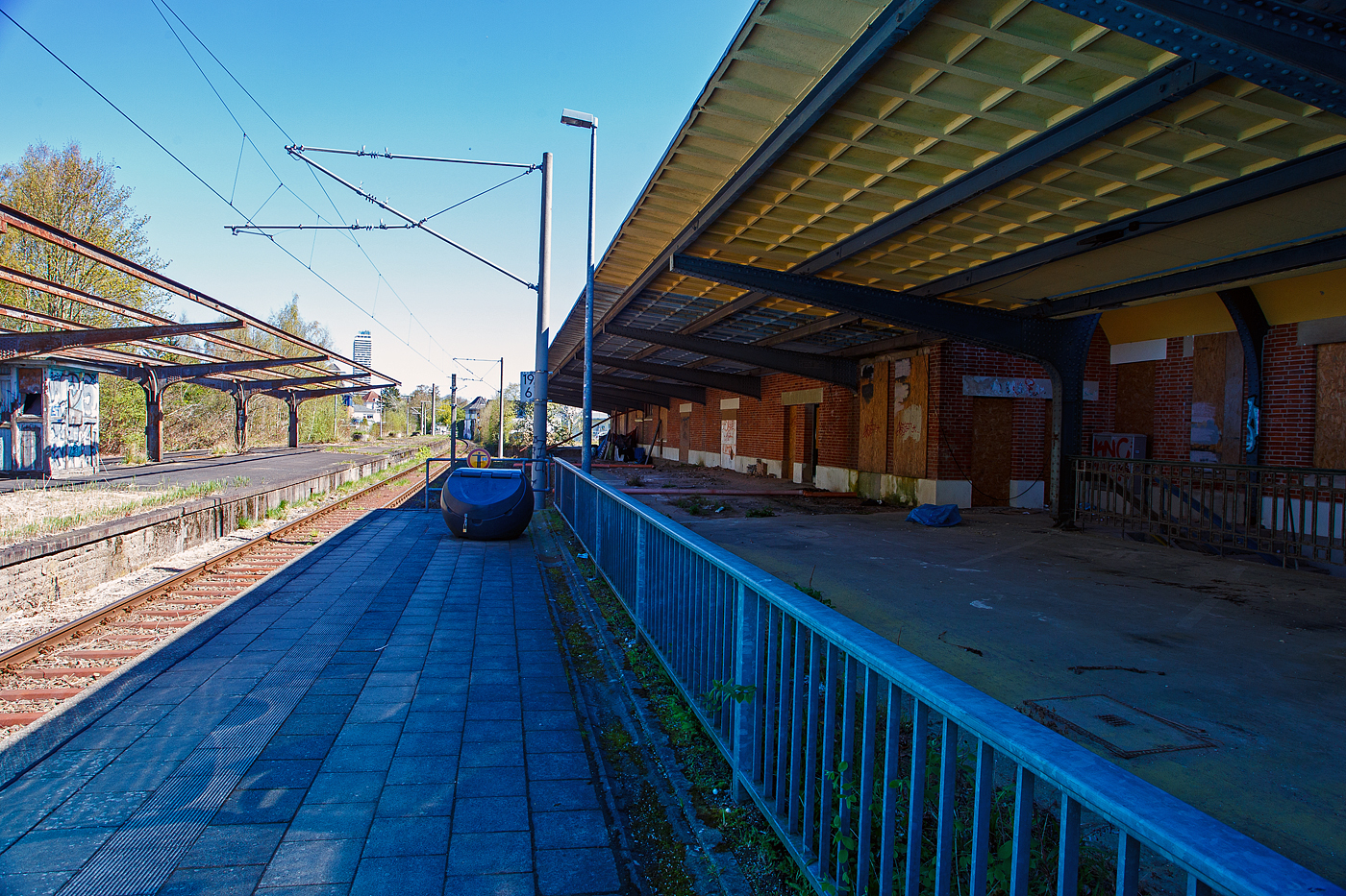 Nicht sehr einladend, der Bahnhof Lübeck-Travemünde Hafen (Hafenbahnhof) am 21 April 2026 in Blickrichtung Strand. Links der aufgegebene Mittelbahnsteig mit den Gleisen 2 (heute Gleis 1) und 3. Auf der Trasse des ehemaligen Gleis 1 am Bahnhofsgebäude befindet sich heute der neue Außenbahnsteig. Und ganz rechts der ehemalige Bahnsteig 1 und das ehemalige Empfangsgebäude.