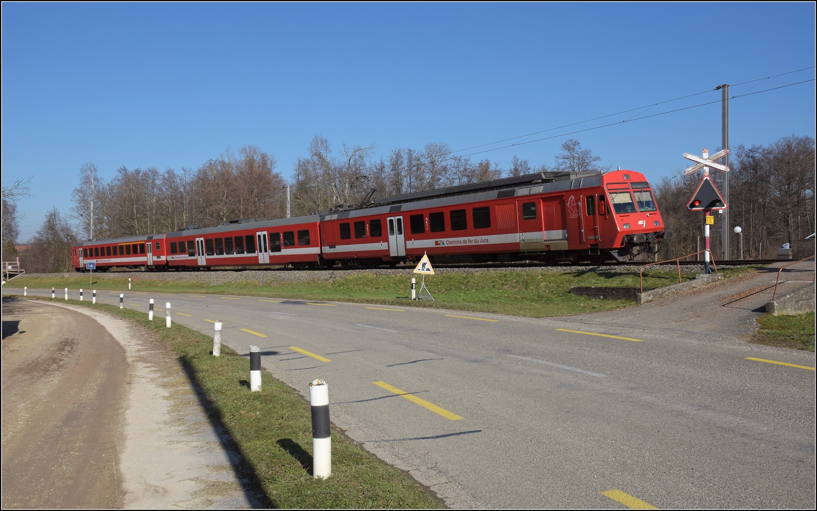 Noch ein bisschen Ajoie.

RABe 567 184 der CJ an einem kleinen altert�mlichen Bahn�bergang vor Bonfol. Februar 2023.