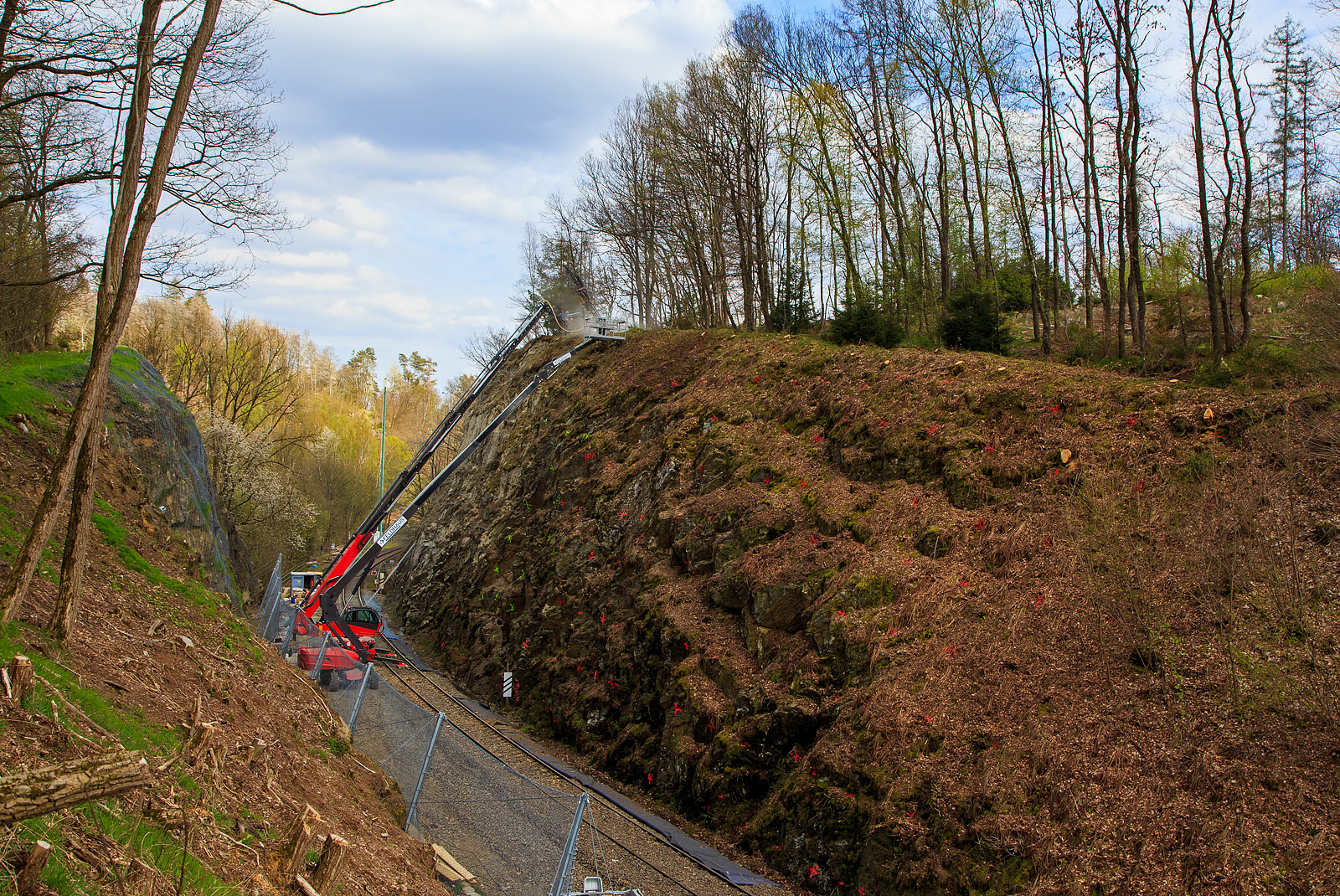 Nun haben die Felssicherungsarbeiten endlich begonnen....
Am 23. Dezember 2022 ca. 18:15 Uhr kam es hier, in Herdorf kurz hinter dem Hp  Königsstollen (bei km 88,4 der Hellertalbahn KBS 462), zu einem Felssturz und der HLB Triebwagen VT 507, als RB 96 „Hellertalbahn“ entgleiste, verletzt wurde zum Glück niemand. Nun nach über vier Monaten haben endlich die erforderlichen Sicherungsmaßnahmen begonnen, hier am 27.04.2023. Zuerst müssen viele 4 m lange Anker in den Fels getrieben werden. Die Arbeiten werden von der Firma FELDHAUS Bergbau GmbH & Co. KG aus Schmallenberg (Hochsauerland) ausgeführt. 
