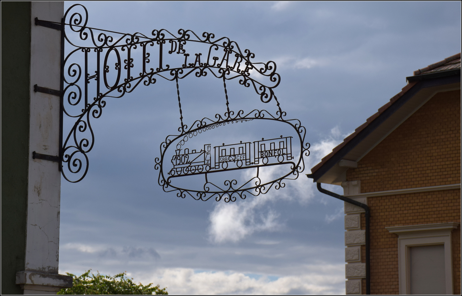 Pumpfel, das Streckenende.

Das Hotel de Gare von Bonfol hat die guten Zeiten längst hinter sich. Nur noch das hübsche schmiedeeiserne Schild zeugt noch von bedeutenden Tagen. Hier dürfte das portugiesische Wort Saudade eine Schweizer Heimat besitzen. Bei der abgebildeten Tenderlok mit der Achsfolge einer Pacific hat der Künstler wohl seine Freiheit genutzt. Mit dieser Achsfolge dürften in der Umgebung wohl nur in Österreich mit der BR 77 eingesetzt worden sein. Mai 2024.