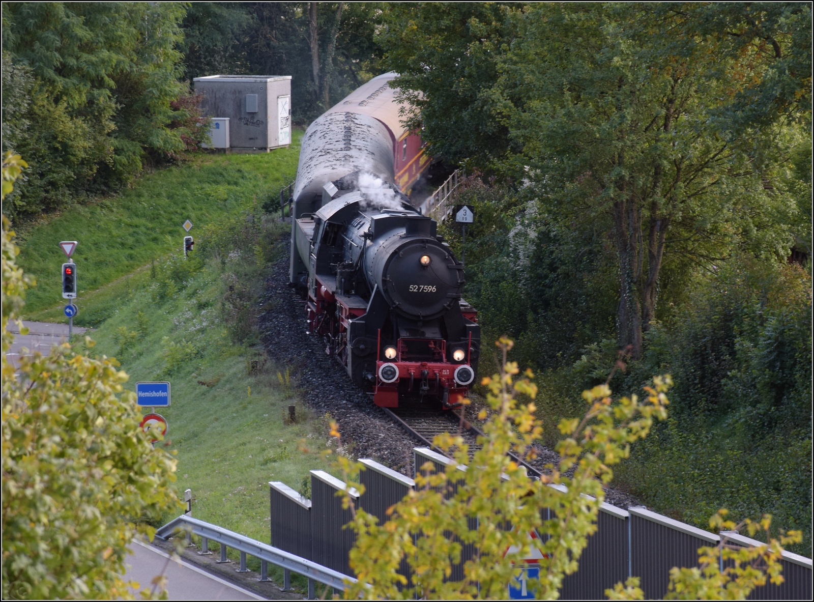 Schienenverkehr am Schienerberg. 

52 7596 mit ihrem EFZ-Sonderzug für die SEHR&RS hat gerade die Rheinbrücke von Hemishofen überquert und erreicht gleich den dortigen Bahnhof. Oktober 2022.