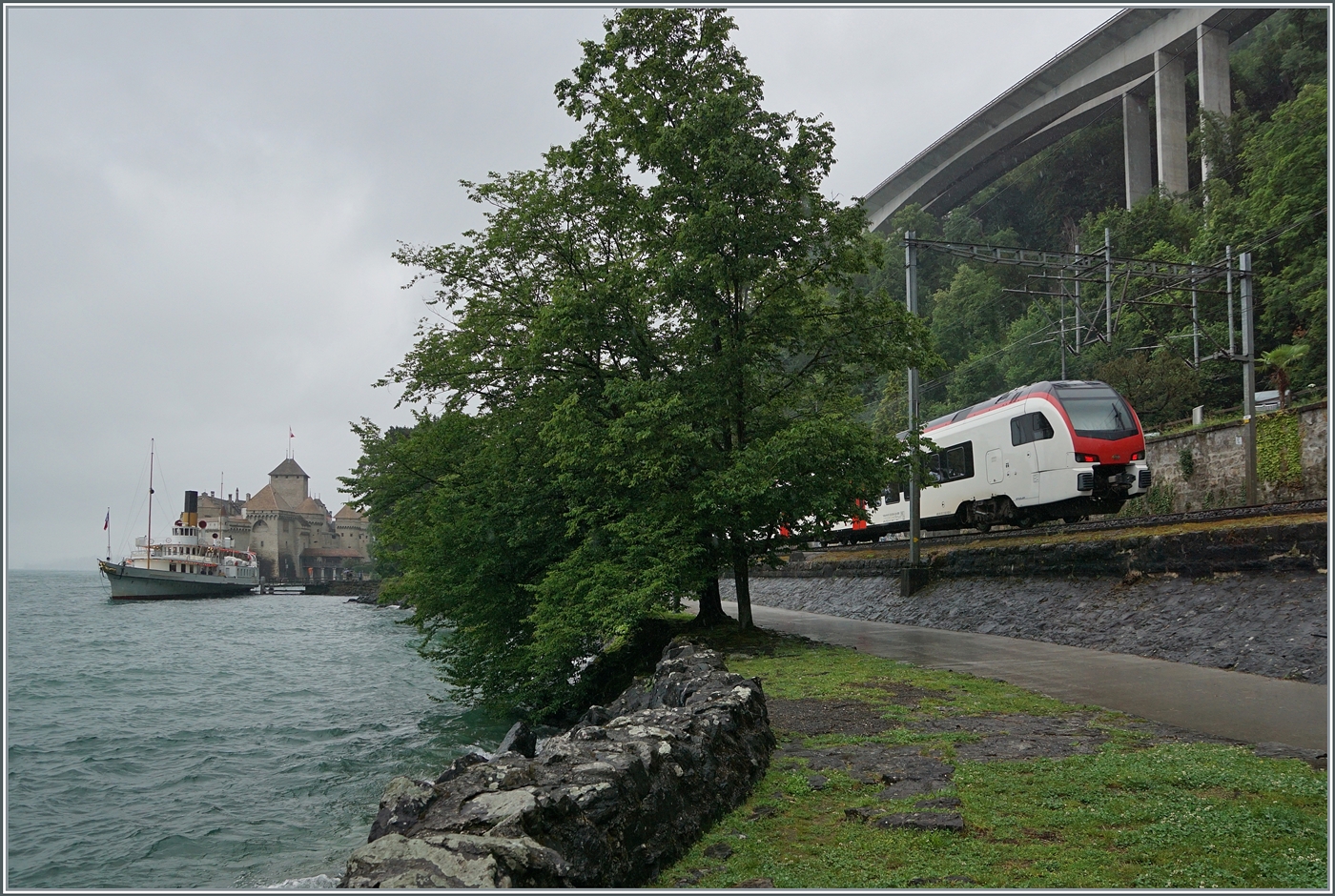 Schiff und Bahn: Während der CGN Schaufelraddampfer  Italie  die Anlegestelle Château de Chillon verlässt, ist ein SBB RABe 523  Mouette  auf der Fahrt nach Lausanne. 

22. Juni 2024