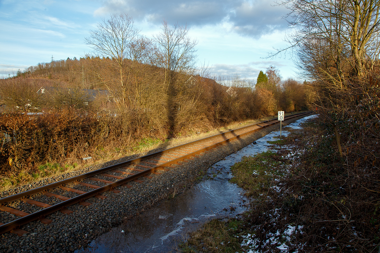 Schlimmer geht immer.....
Totalsperrung der Hellertalbahn (KBS 462 / Strecke 2651)
Nun ist Herdorf Bahntechnisch zur Insel geworden. 
Es gibt seit dem 10.03.23 eine Gleisunterspülung auf der Strecke 2651 bei km 91,0, so ist vorerst auch kein Güterverkehr von Haiger nach Herdorf möglich. Da die Strecke Betzdorf – Herdorf, bereits wegen dem Felsstutz  am 23.12.2022, seitdem gesperrt ist Herdorf nun Bahntechnisch ganz abgeschnitten. 

Eigentlich hatte ich am Mittag (11.03.2023) gedacht das Wasser fließt nun einfach ab. Aber leider war es am Nachmittag noch nicht so, der Wasserstand ist leider nur etwas gesunken.

Hier stehe ich nun am Funkmast, von hinten wo der in Arbeiter mit orangen Arbeitsjacke steht, kommt das Wasser bis hier geflossen und sucht sich den Weg unter dem Gleisbett hindurch auf die andere Seite.