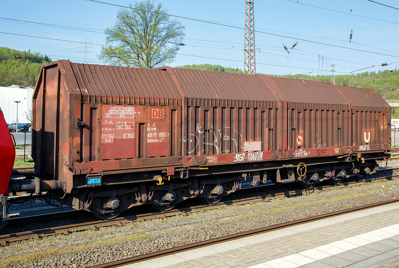 Sechsachsiger Drehgestellflachwagen für Coiltransporte mit verschiebbaren Teleskophauben und Lademulden für Coiltransporte, 31 80 4876 652-7 D-DB der Gattung Sahimms-u 900, der DB Cargo AG, am 20.04.2018  in Kreuztal.

LHB und Talbot entwickeln einen 6-achsigen Haubenwagen für den Transport schwerer Coils, von dem 1981 sechs Prototypen geliefert und bei der DB als Sahimms 900 bezeichnet werden. Dieser Wagen wurde 1984 von der Waggonfabrik Talbot in Aachengebaut.

Die Wagenabdeckung besteht aus vier verschiebbaren Stahl-Teleskophauben, die sich einseitig oder zu beiden Wagen enden hin soweit übereinander schieben lassen, dass jeweils 40% der gesamten Ladelänge freigelegt sind. Die Wagen besitzen insgesamt fünf feste Mulden, wobei die beiden äußeren Mulden Coils mit einem Gewicht von maximal 25 t und einem maximalen Durchmesser von 2.250 mm, die mittleren drei Mulden Coils mit maximal 45 t Gewicht bei einem maximalen Durchmesser von 2.700 mm aufnehmen können. 

Im Jahre 1984 erfolgt ein Serienbau von 300 Teleskophaubenwagen. 1986/87 baut Waggonbau Niesky eine Serie von 145 Wagen, mit Drehgestellen von Graaff.

Ab 1997 werden im DB Werk Paderborn zum Schutz gegen Transportschäden die Mulden von Sahimms 900 mit gewebeverstärkten Gummimatten ausgekleidet und die Wagen wurden in Sahimms-u 900 umgezeichnet.

TECHNISCHE DATEN:
Gattungszeichen mit Bauartnummer: Sahimms-u 900
Spurweite: 1.435 mm
Anzahl der Radsätze: 6 (in zwei Drehgestellen)
Länge über Puffer: 15.000 mm
Drehzapfenabstand: 8.000 mm
Achsabstände in den Drehgestellen: 2 x 1.700 mm = 3.400 mm
Ladebreite in den Mulden: 2.400 mm
max. Durchmesser der Coils: 2.700 mm
Wagenhöhe: 4.148 mm
Anzahl der Radsätze: 6 (in zwei Drehgestellen)
Eigengewicht: 32.850 kg
Max. Zuladung bei Lastgrenze S: 72,0 t (ab Streckenklasse D2)
Max. Zuladung bei Lastgrenze S auf DB-Netz: 87,0 t (ab CE)
max. Tragfähigkeit: 99 t
Höchstgeschwindigkeit: 100 km/h (beladen) / 120 km/h (leer)
Bremse: KE-GP (LL)
Bremssohle: IB 116
Handbremse: Ja
kleinster befahrbarer Gleisbogen: R 75 m
Intern. Verwendungsfähigkeit: RIV