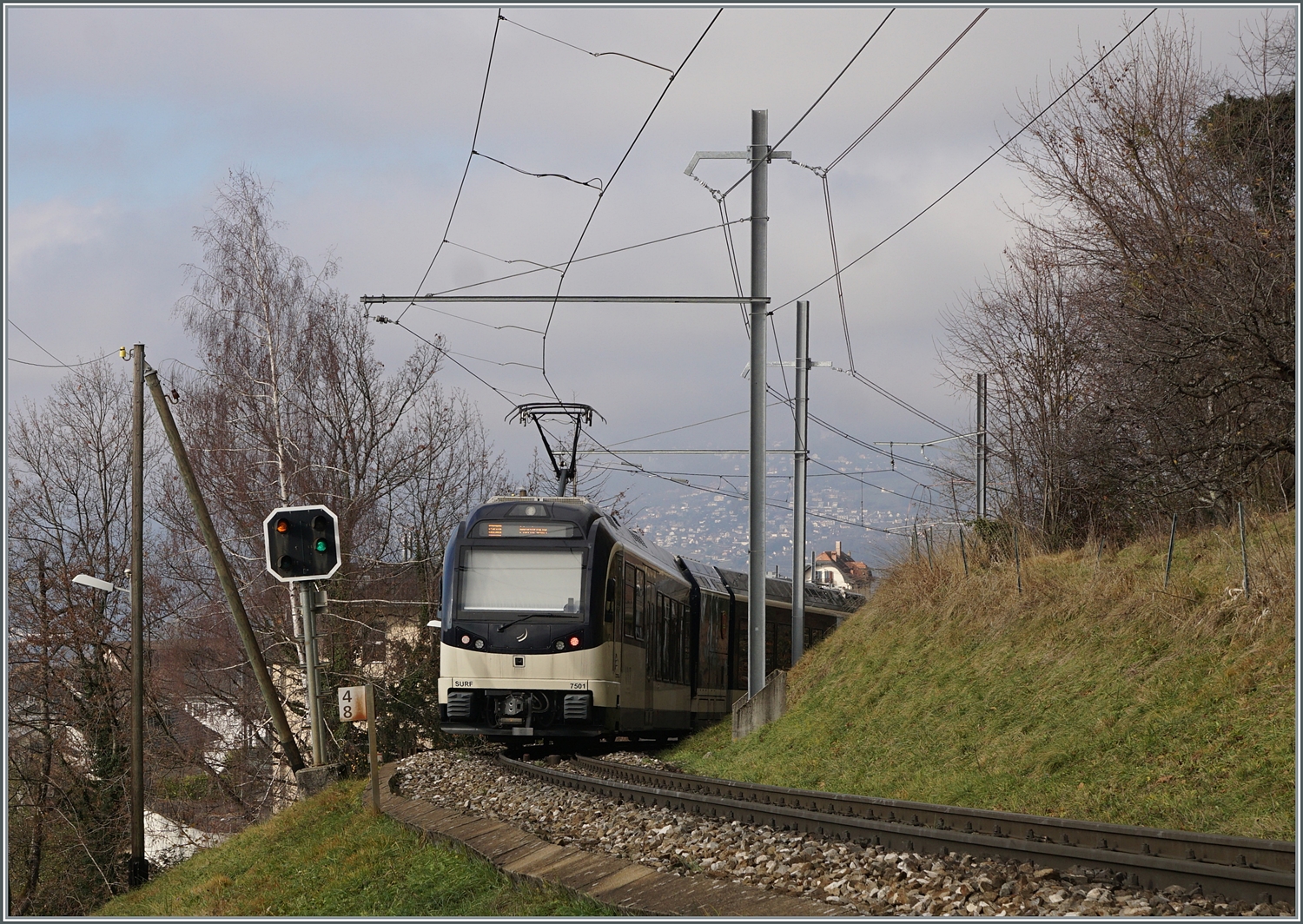 Unter eine  Windschiefen Fahrleitung  (offizielle Namensgebung dieser nur am oberen Tragseil befestigten Fahrleitung) und einem recht schiefen Vorsignal von Chernex ist der CEV MVR ABeh 2/6 7501  Saint-Légier-La-Chiesaz  auf dem Weg von Les Avants nach Montreux. 

17. Dez. 2023