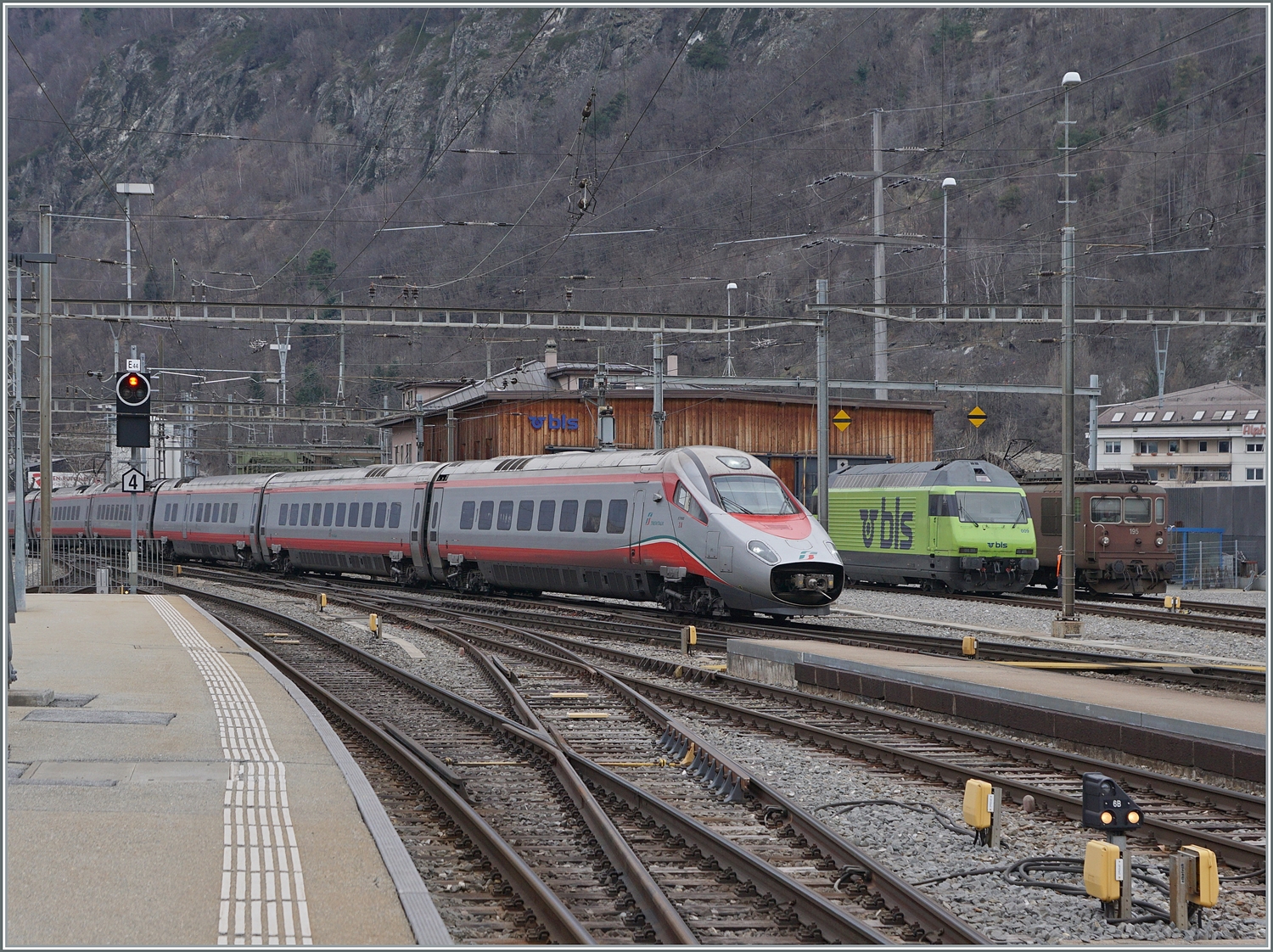 Vor dem Hintergrund der beiden BLS Loks  Re 465 009 und Re 4/4 195 erreicht ein FS Trenitalia ETR 610 auf dem Weg nach Milano den Bahnhof von Brig. 

2. Feb. 2024