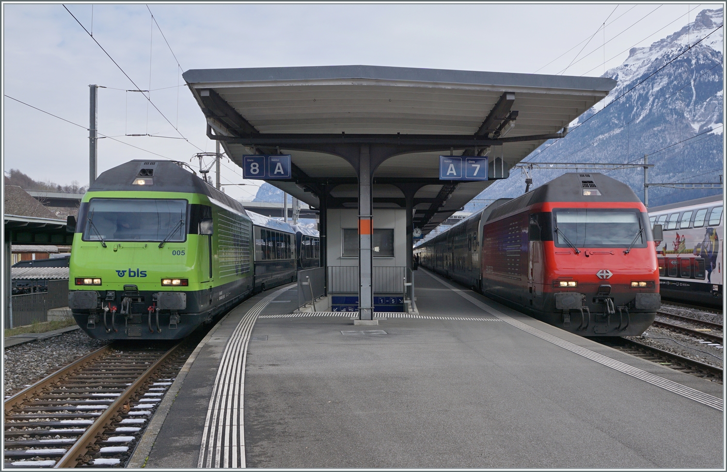 Zwei Re 460 / 465 Loks warten mit Reisezügen auf die Abfahrt: Links im Bild die BLS Re 465 005 mit dem GoldenPass Express GPX 4075 nach Montreux und eine SBB Re 460 mit ihrem IC 61 972 nach Basel SBB. 

16. Januar 2024