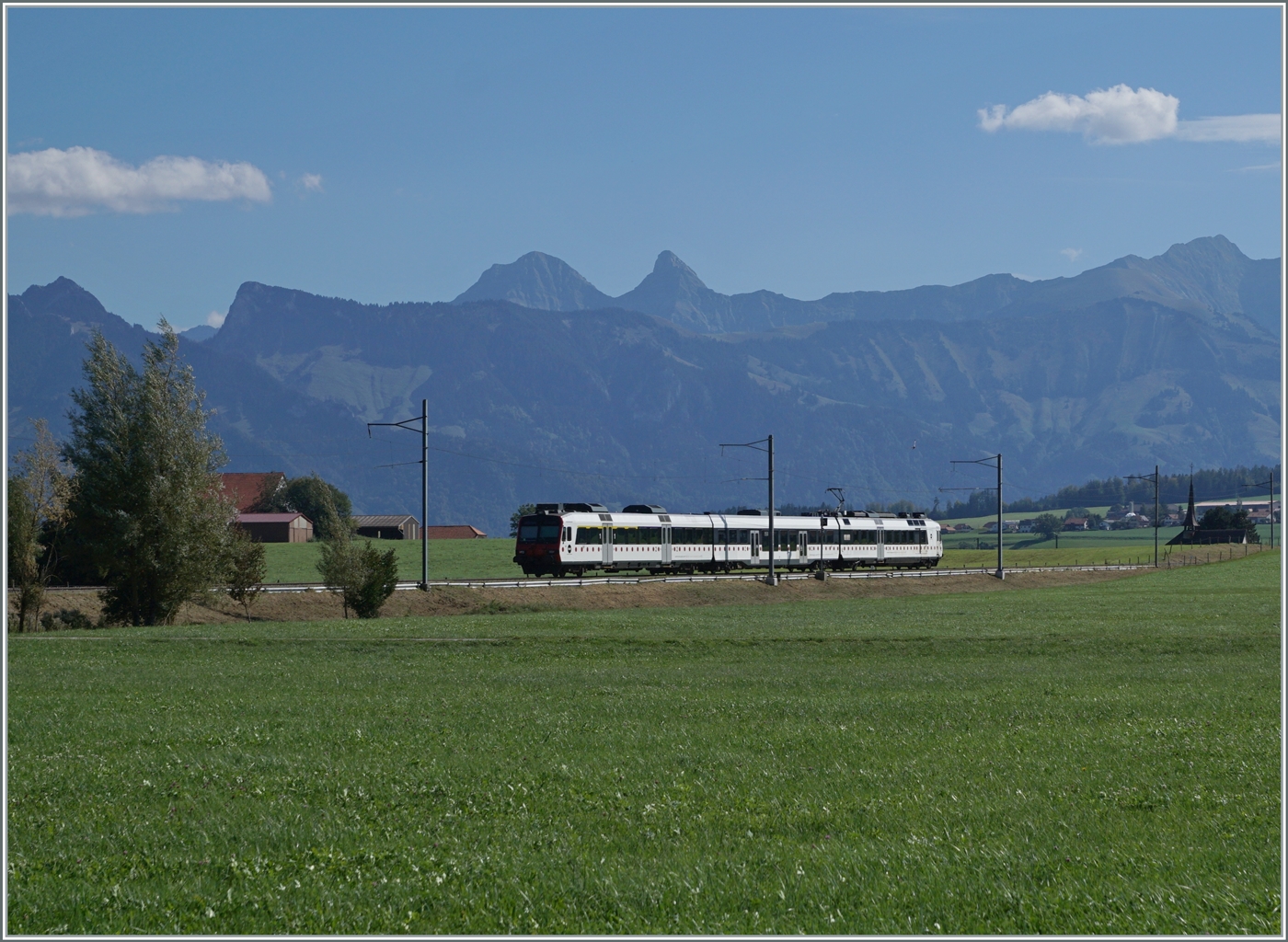 Zwischen Sâles und Vaulruz ist ein TPF RBDe 560 Domino auf dem Weg nach Broc Fabrique. 
Im Hintergrund die Freiburger Alpen. 

29. Sept. 2023