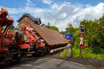 Drehgestellflachwagen f�r den Transport von Blechtafeln, 31 80 4726 064-7 D-DB, der Gattung Slps-u 725, der DB Cargo Deutschland AG am 20 Mai 2026 im Zugverband bei der Zugdurchfahrt in Kirchen/Sieg in Richtung Siegen. Hier beladen mit Gro�blechen mit einer Breite von ca. 4 m. 

Der Slps-u 725 ist ein Schr�glader und besonders f�r den Transport von Gro�blechen bis zu einer Breite von 5,50 m geeignet. Durch die Schr�gstellung der Ladeger�ste k�nnen Bleche bis zu 3.970 mm ohne Ladema��berschreitung bef�rdert werden, was man hier im beladenen Zustand gut sehen kann. 

Diese Flachwagenbauart ist f�r den Transport von Gro�blechen vorgesehen, wobei f�r die Be- und Entladung die waagerechte Lage des hydraulisch schwenkbaren Ladeger�stes vorteilhaft ist. Zur optimalen Ausnutzung der jeweiligen Begrenzungen beim Transport ist jedoch eine der vielen einstellbaren Schr�glagen m�glich.

Das vollst�ndig geschwei�te Untergestell besteht aus einem Hohltr�ger, die beiden Hauptquertr�ger und die Kopfst�cke, die f�r den Einbau der Automatische Kupplung (Z-AK) vorbereitet sind. Fest verschwei�t mit dem Untergestell sind die Tragkonsolen f�r die Ladeger�ste.

Die Ladeeinrichtung besteht aus drei Ladeger�sten, die in Stufen von 2� bis 50� (Mittelger�st bis 60�) schwenkbar sind. An beiden Seiten des Ladeger�stes sind zur Breiteneinstellung f�r Ladeg�ter von 2.850 mm bis 5.500 mm in Stufen von 20 mm von Hand verstellbare Schubriegel vorhanden, die durch Sicherungsbolzen gehalten werden. Zum Sichern des Ladegutes sind die Enden aller Schubriegel mit Halteklauen versehen, im mittleren Bereich sind Ladeschwellen angeordnet. Zur Ladegutsicherung sind an jedem Quertr�ger (Schubriegel) Spanngurte mit Winde und Kantenschutz vorhanden. An den Stirnenden der �u�eren Ladeger�ste sind kurze feste Rungen zur Aufnahme der L�ngskr�fte vorhanden. Au�erdem sind auf den Ladeger�sten versenkbare Rungen zur Aufnahme der L�ngskr�fte bei kurzen Ladungen vorhanden (L�ngenverteilung).

Das Ladeger�st kann mit dem Ladegut durch eine einfach zu bedienende und betriebssichere hydraulische Einrichtung nach einer Seite geschwenkt werden. Sie besteht aus vier mit einer Synchronisiereinrichtung ausger�steten Differentialzylindern, die zwischen Untergestell und Ladeger�st angeordnet sind, einem E-Motor-Pumpen-Aggregat mit �lbeh�lter, Sicherheitsventil und drei Handsteuerventilen. Die Ladeger�ste werden durch hydraulische Sperrventile in allen Lagen gesichert und zus�tzlich in den End- und Zwischenstellungen mechanisch gesichert. F�r den Schwenkvorgang von 0� bis 50� werden ca. 5 Minuten ben�tigt.

TECHNISCHE DATEN:
Achsanzahl: 4
Drehzapfenabstand: 17.000 mm
Achsabstand im Drehgestell: 1.800 mm
L�nge �ber Puffer: 22.040 mm
Max. Ladel�nge: 19.000 mm
Eigengewicht: 32.310 kg
Kleinster befahrbarer Radius: Ladeger�st waagerecht und bis 44� geneigt 60 m, bis 46� geneigt 75 m
bis 48� geneigt 90 m
bis 50� geneigt 140 m
Lastgrenze bei Streckenklasse D: 57,5 t / DB CM 51,5 t
Bremse: KE-GP-A
Bremssohle: IB 116
Feststellbremse: keine
Verwendungsf�higkeit: RIV

