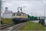 Die IRSI/IGE  Rheingold  Re 4/4 II 11387 (Re 421 387-2) im Dienste der BAM MBC verlässt mit ihrem Kieszug nach Apples das Industriegelände bei Gland. 

22. Feb. 2024